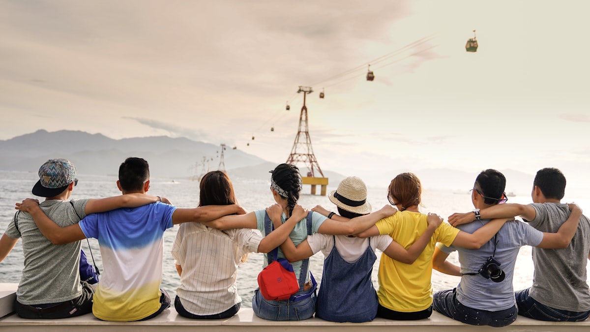 Group of friends sitting together with arms around each other looking out at the view